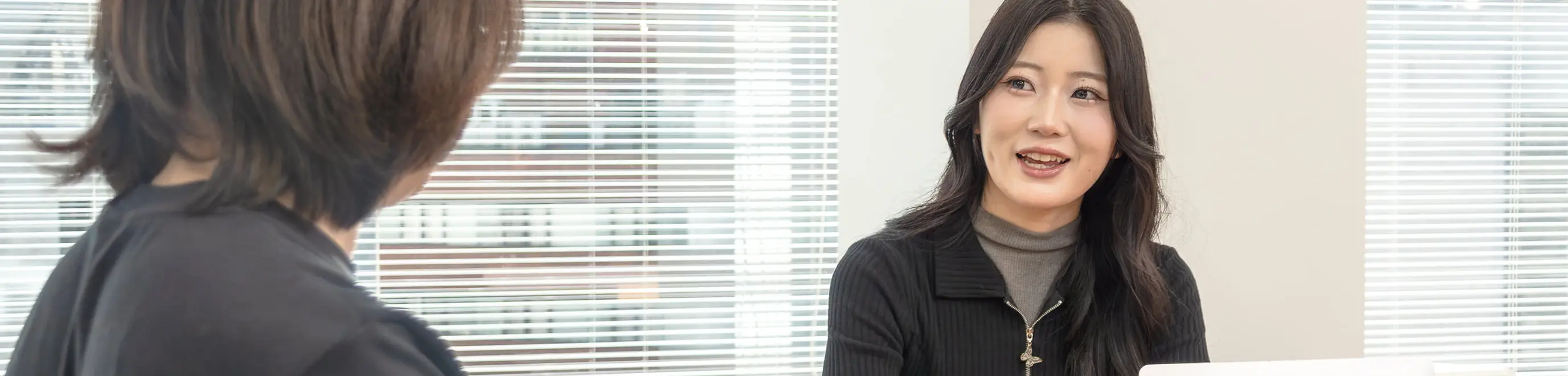 テーブルを挟んでノートパソコンを見ながら話し合う2人のビジネスパーソン