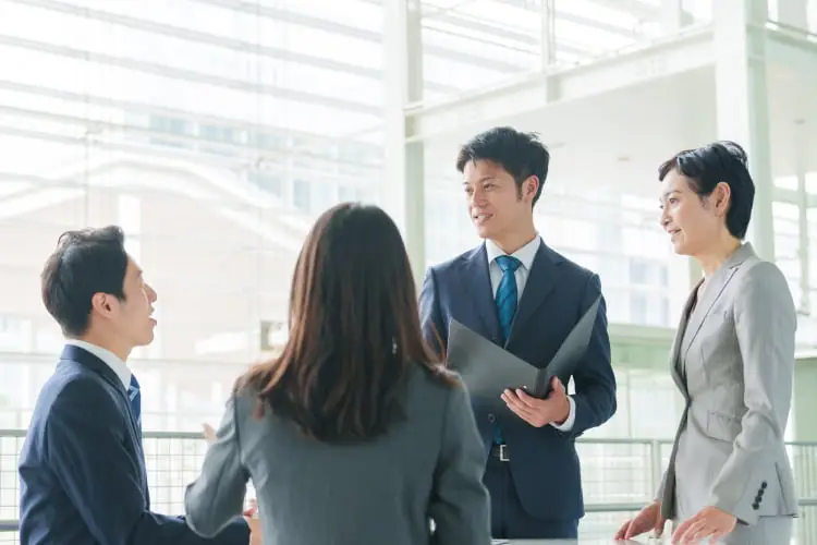 MOMENTUMのロゴが表示されたプレゼンテーション画面を指差す男性と、それを見る人物