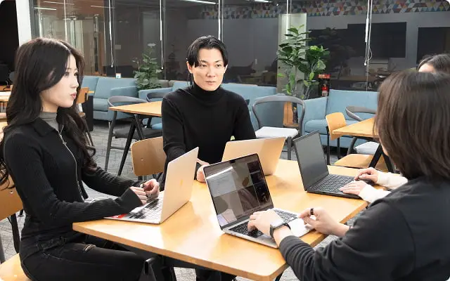 オフィスでノートパソコンを使って作業する4人のビジネスパーソン