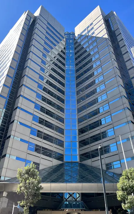 青いガラスと白いパネルが特徴的な高層ビル