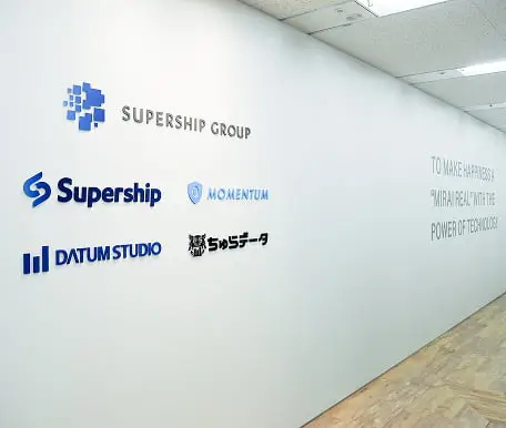 グループ企業ロゴとミッションステートメントが描かれたオフィス壁面