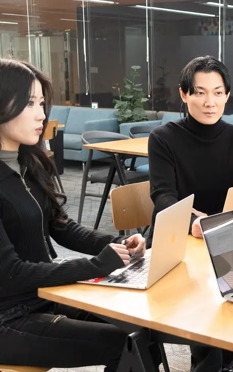 オフィスでノートパソコンを前に打ち合わせをする2人のビジネスパーソン