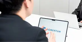 タブレットとノートパソコンを使って打ち合わせをする2人のビジネスパーソン