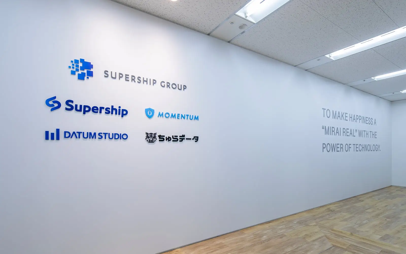 企業ロゴとミッションステートメントが掲げられたオフィス壁面